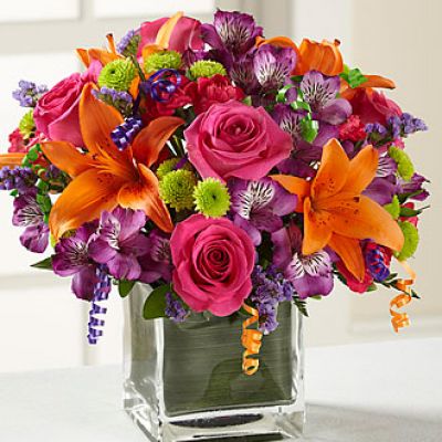 Birthday blooms that are ready to get your recipient's special day started, this flower bouquet is bright, happy, and ready to celebrate! Hot pink roses and orange Asiatic Lilies are vibrant and fun surrounded by purple Peruvian Lilies, hot pink mini carnations, green button poms, purple statice, and an assortment of lush greens. Accented with assorted curling ribbons to give it that party feels and presented in a clear glass cubed vase lined with ti leaf green material for added beauty, this unforgettable birthday bouquet is that ultimate surprise that will make them feel the love on their big day.
STANDARD bouquet includes 11 stems.
Approximately 10H x 10W.
C Quantity Color Description
2 Hot Pink 50 cm Standard Rose
1 Orange Asiatic Lily
3 Purple Alstroemeria
2 Green Button Pom
2 Hot Pink Miniature Carnation
1 Purple Filler - Sinuata Statice
2 Green Green - Leather Leaf
1 Green Green - Pittosporum
0.33 Green Green Flexible Leaf Material
1.5 Curling Ribbon (yds.)
0.33 Green Florist Foam Brick
DELUXE bouquet includes 15 stems.
Approximately 11H x 11W.
C Quantity Color Description
4 Hot Pink 50 cm Standard Rose
1 Orange Asiatic Lily
3 Purple Alstroemeria
2 Green Button Pom
3 Hot Pink Miniature Carnation
2 Purple Filler - Sinuata Statice
2 Green Green - Leather Leaf
1 Green Green - Pittosporum
0.33 Green Green Flexible Leaf Material
1.5 Curling Ribbon (yds.)
0.33 Green Florist Foam Brick
PREMIUM bouquet includes 19 stems.
Approximately 12H x 12W.
C Quantity Color Description
5 Hot Pink 50 cm Standard Rose
2 Orange Asiatic Lily
4 Purple Alstroemeria
3 Green Button Pom
3 Hot Pink Miniature Carnation
2 Purple Filler - Sinuata Statice
2 Green Green - Leather Leaf
1 Green Green - Pittosporum
0.66 Green Green Flexible Leaf Material
3 Curling Ribbon (yds.)
0.5 Green Florist Foam Brick